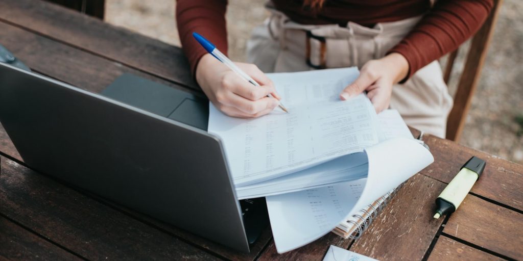 person using a pen to mark financial documents