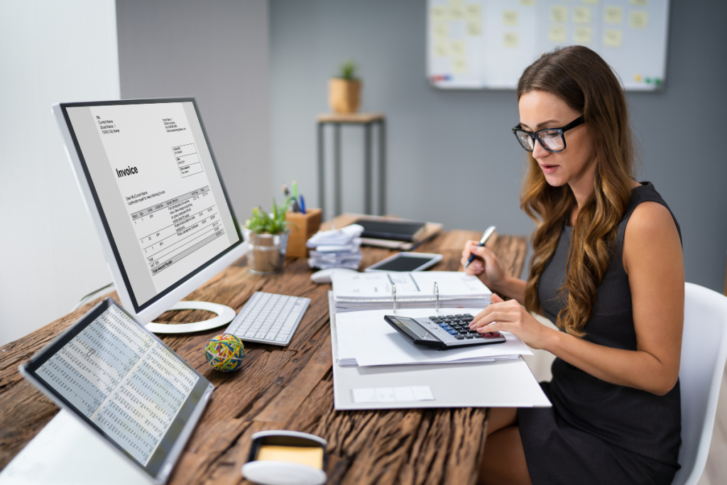CPA with glasses sits in front of computer while using a calculator