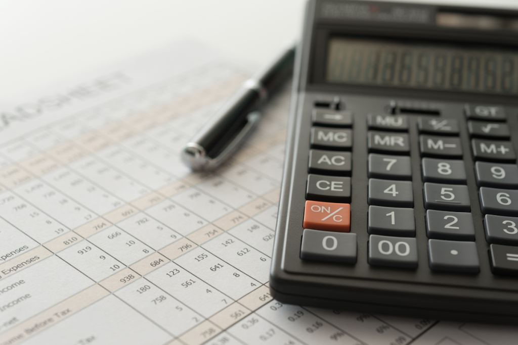 Calculator and pen sit on top of a paper with numbers 